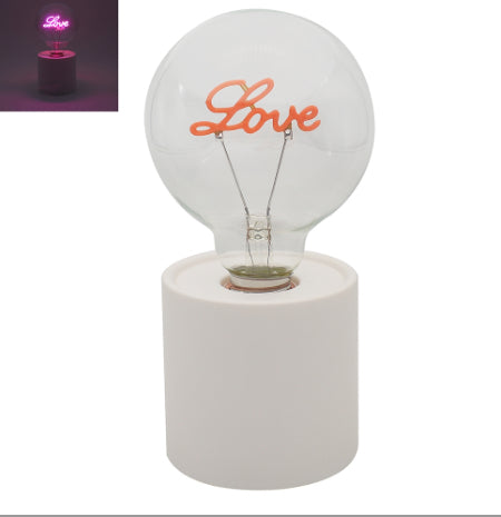 LED love lightbulb on white round cylindrical base. Lights up in neon pink. 