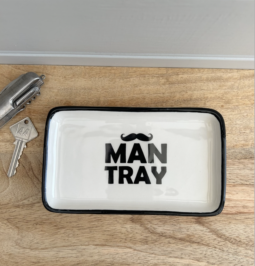 a white ceramic man tray for storage. black edge and black moustache and man tray painted in centre. 